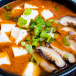 vegetarian kimchi tofu stew topped with mushrooms and scallion