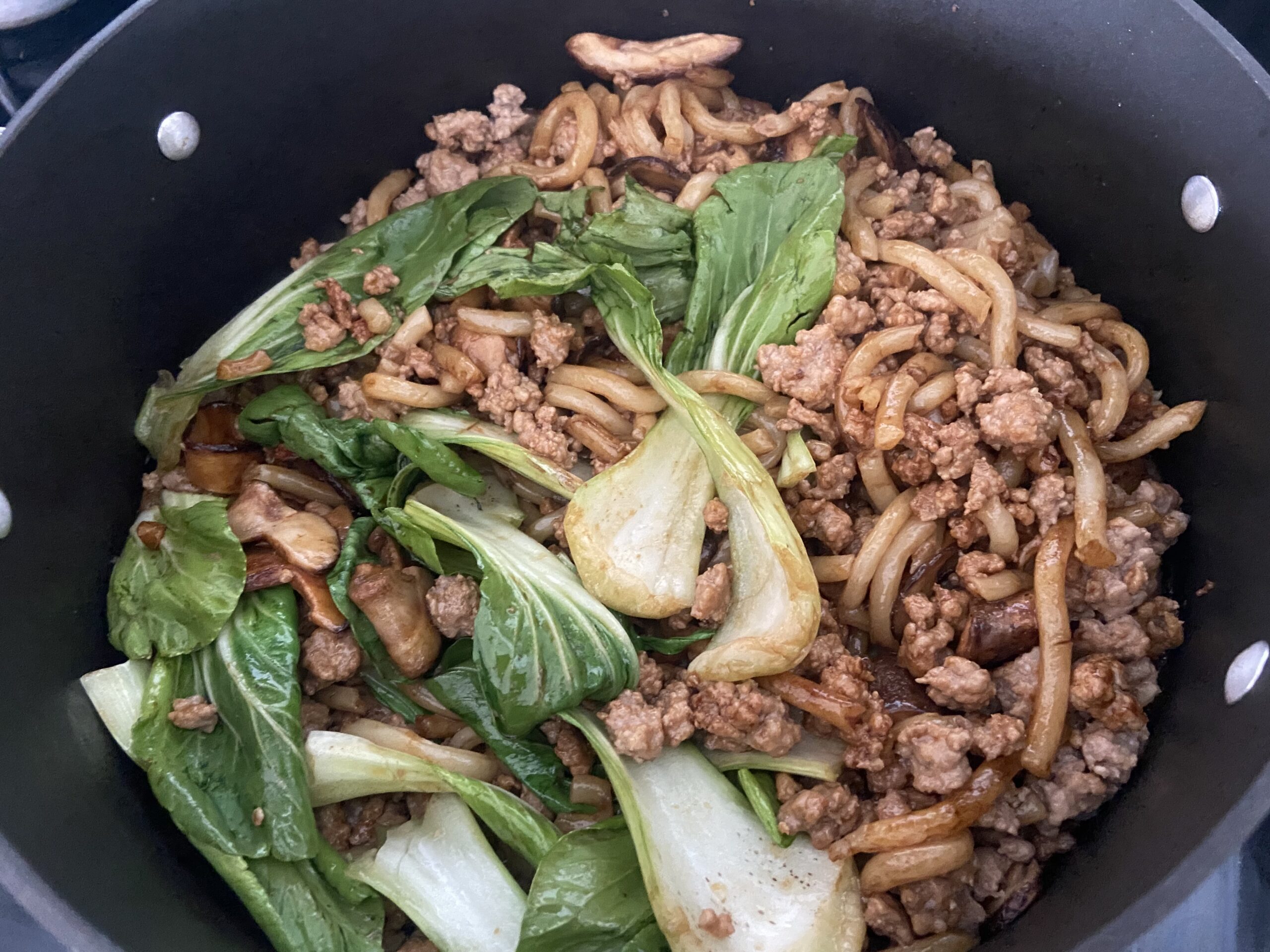 bok choy, ground pork, and noodles cooked in a pan