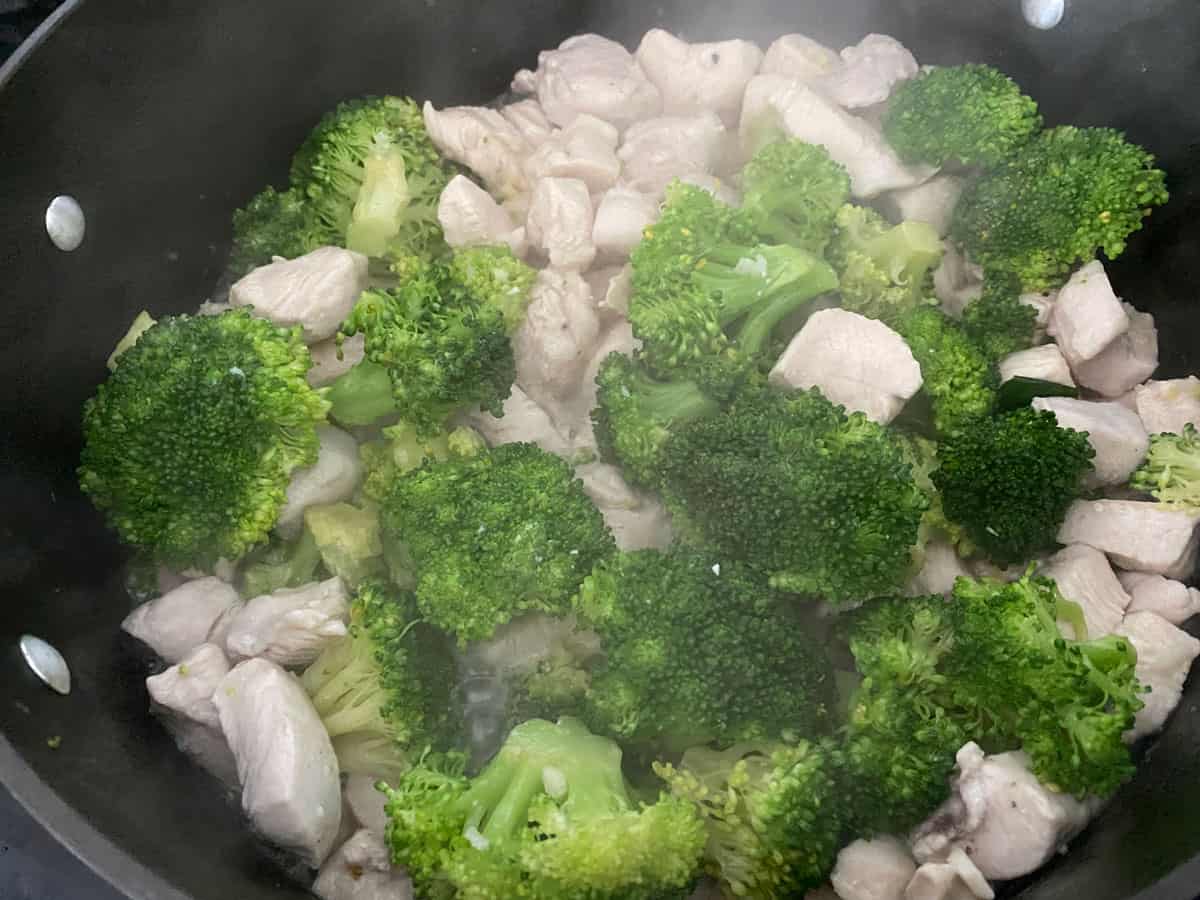 Chicken and broccoli cooking in a pan.