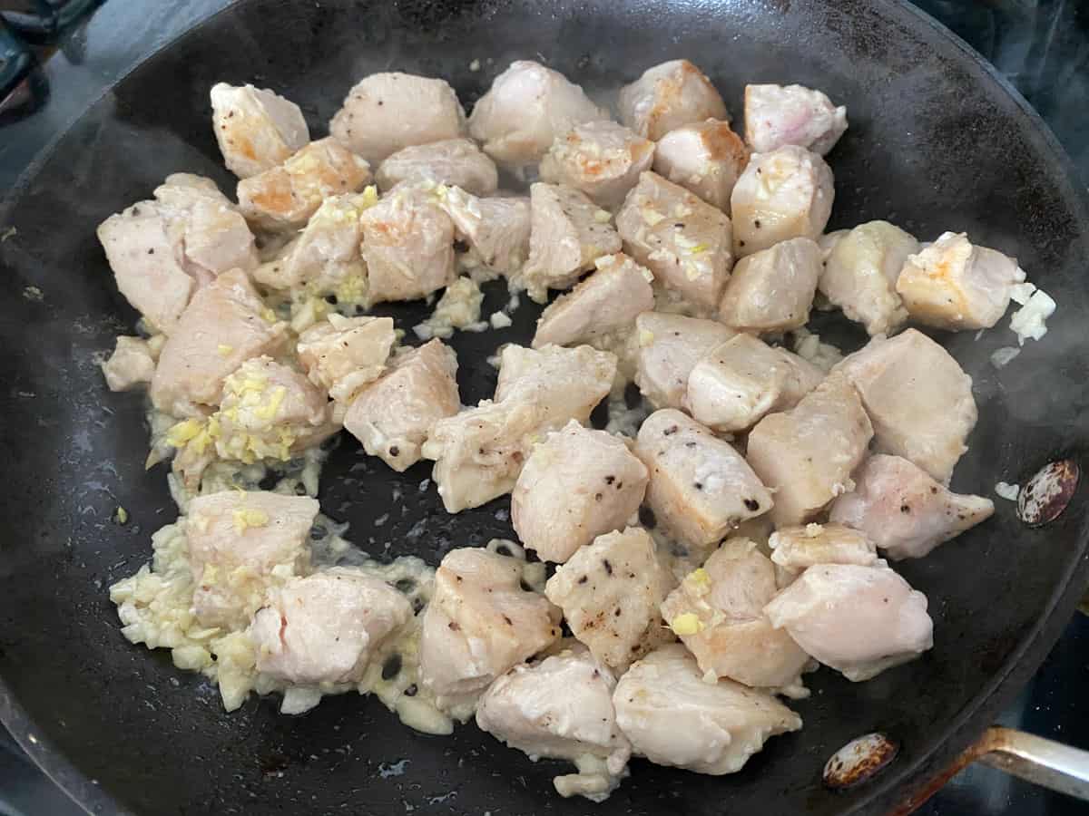 Chicken, garlic, and ginger cooking in a pan.