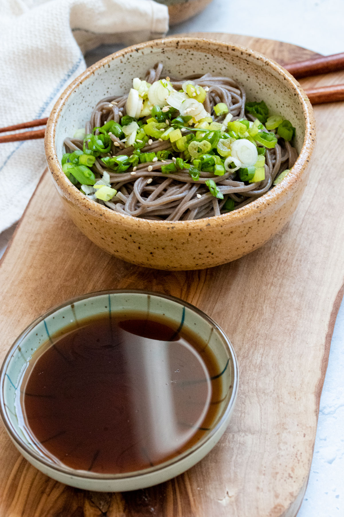 Soba noodles in bowl with dipping sauce on the side.