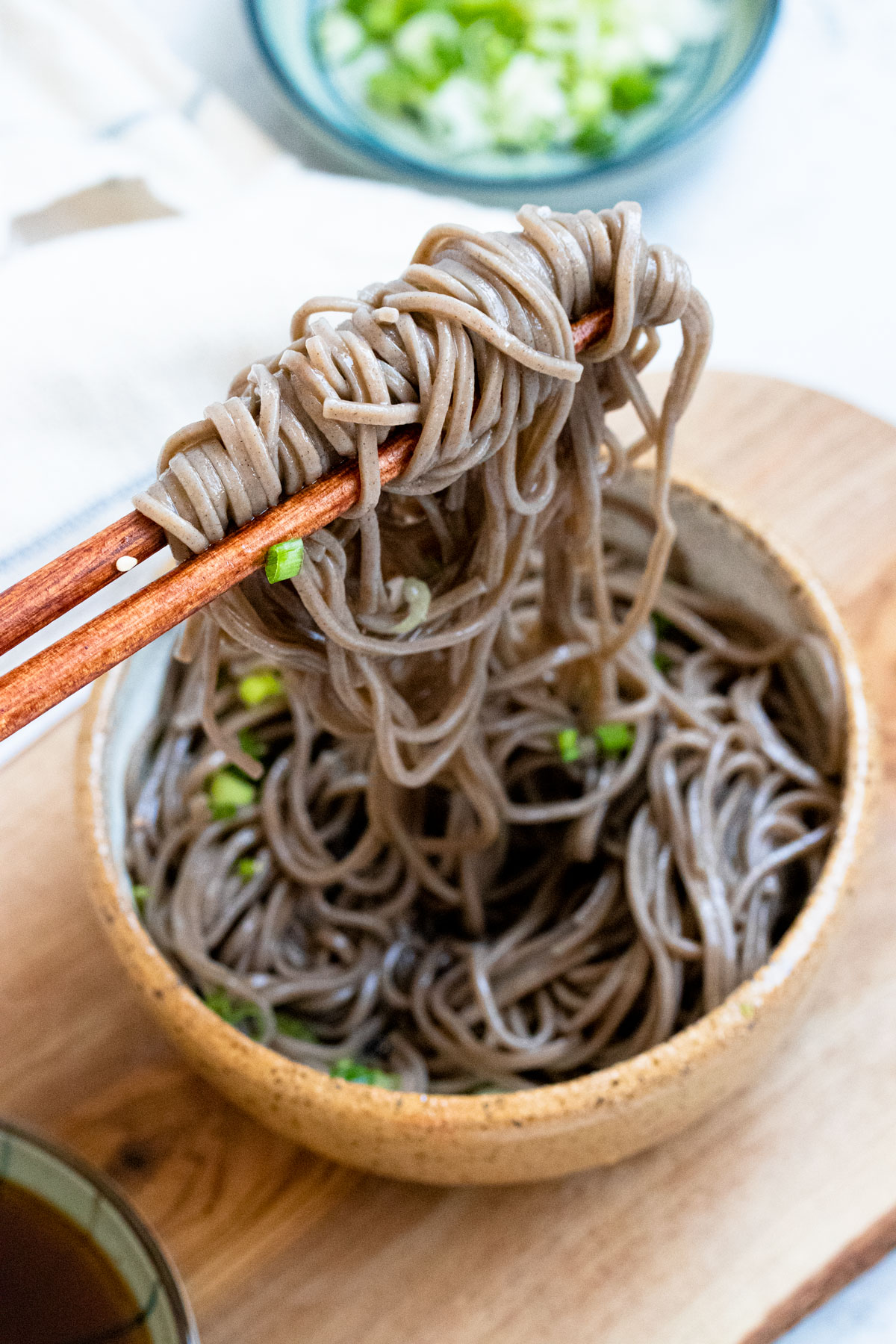 Chopsticks picking up soba noodles.