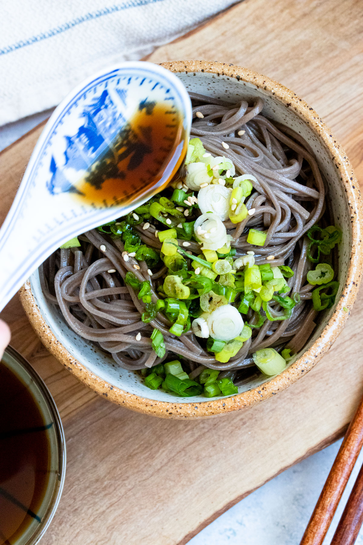 Pouring dipping sauce over soba.