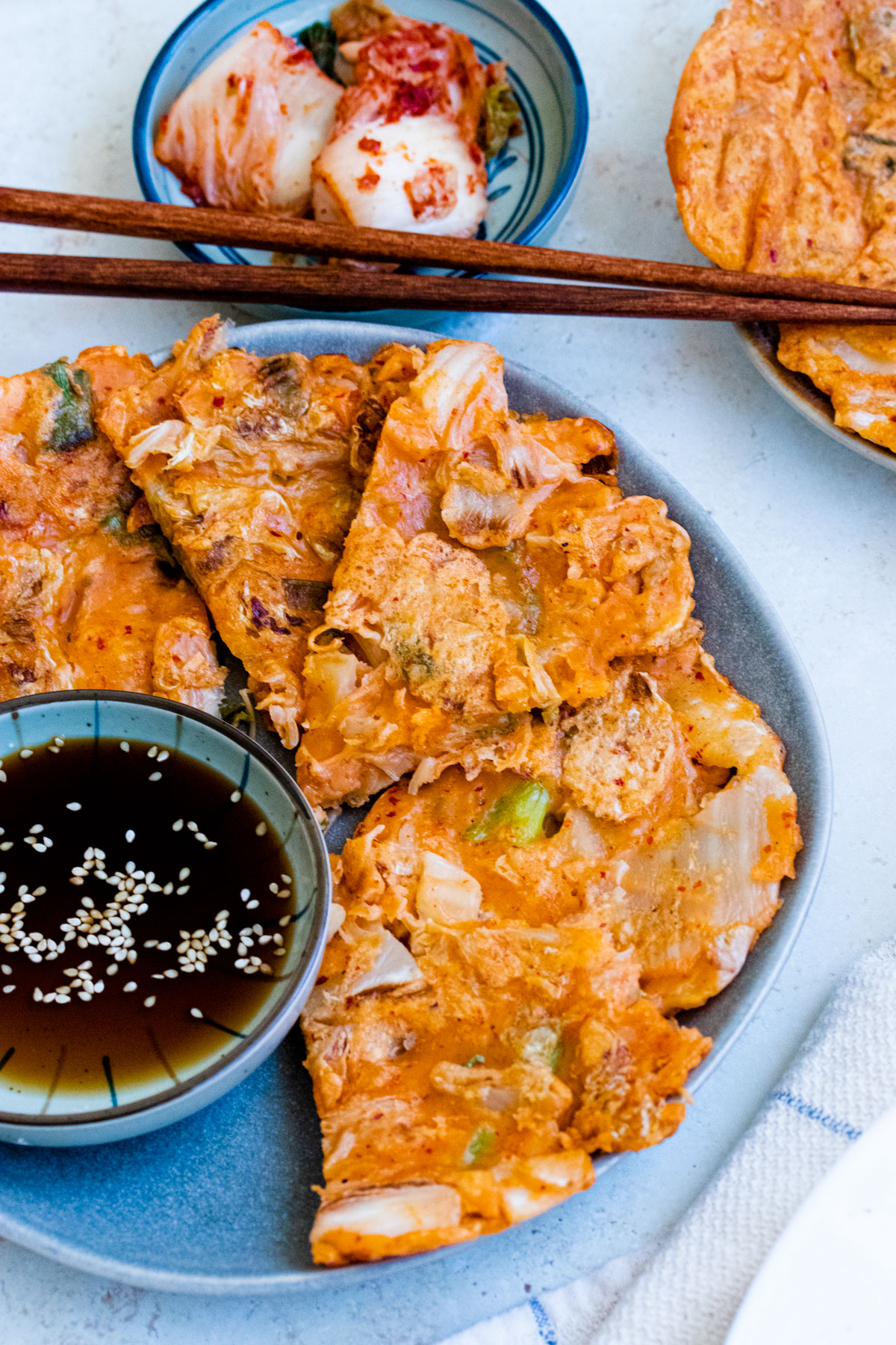 Kimchi pancake on a plate with dipping sauce on the side.