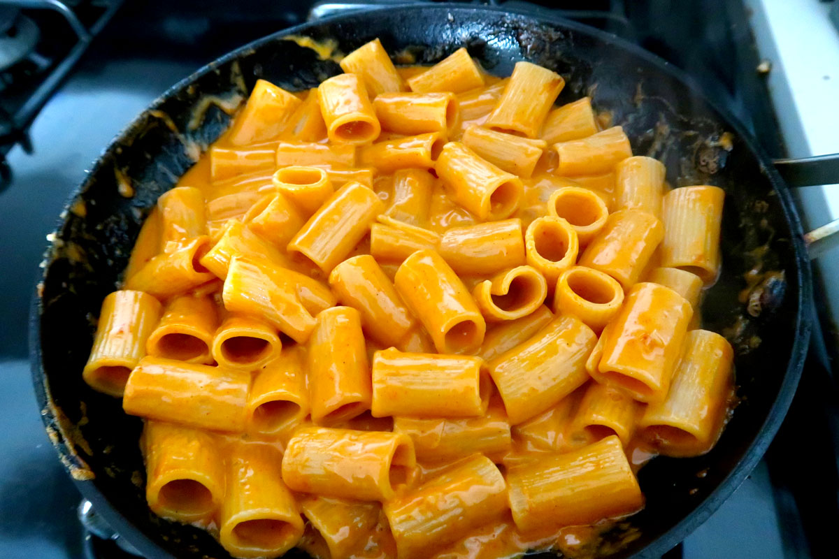 Rigatoni cooking in gochujang sauce on pan.