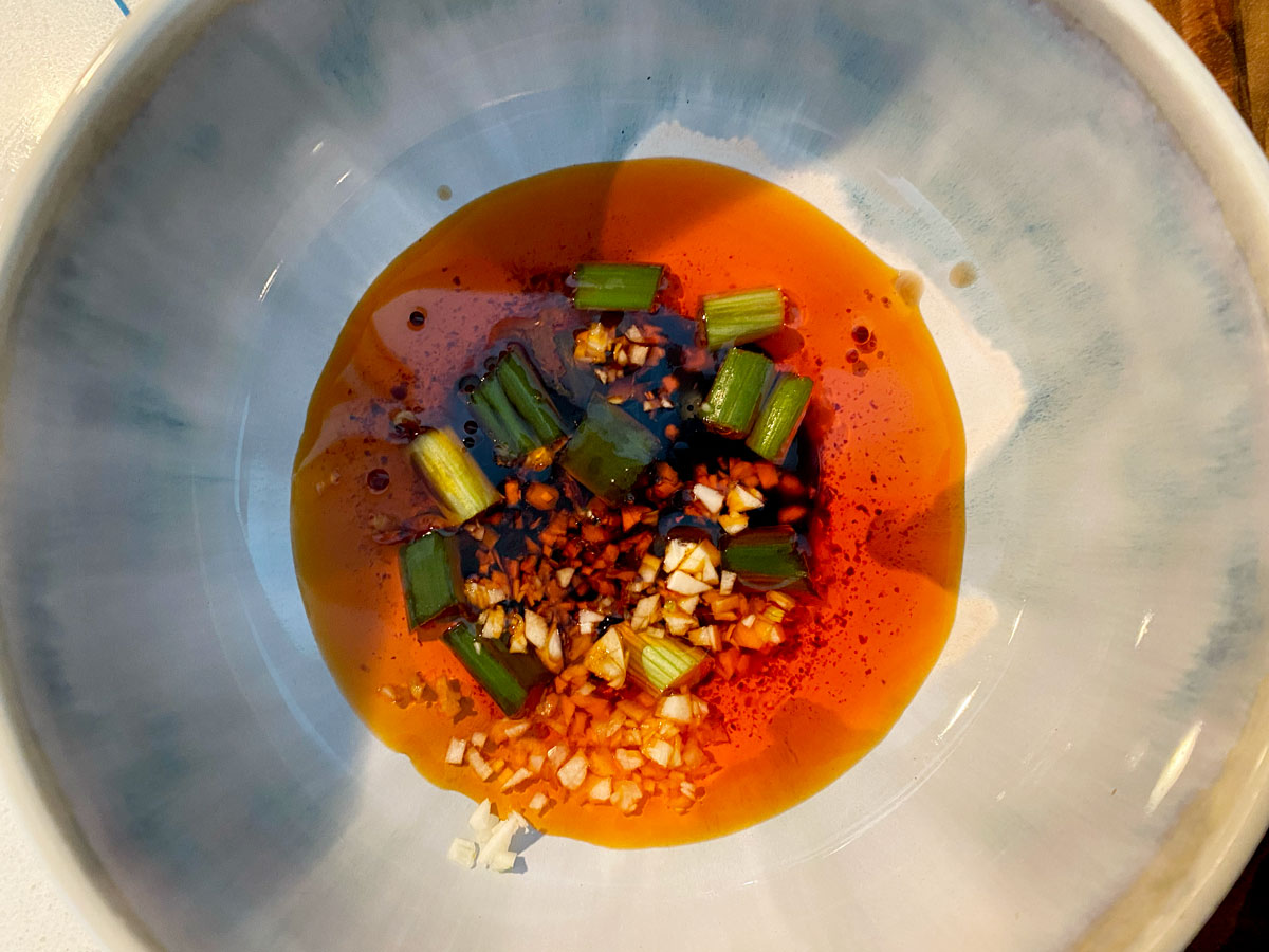 Chili oil, vinegar, soy sauce, scallion, and garlic in a bowl.