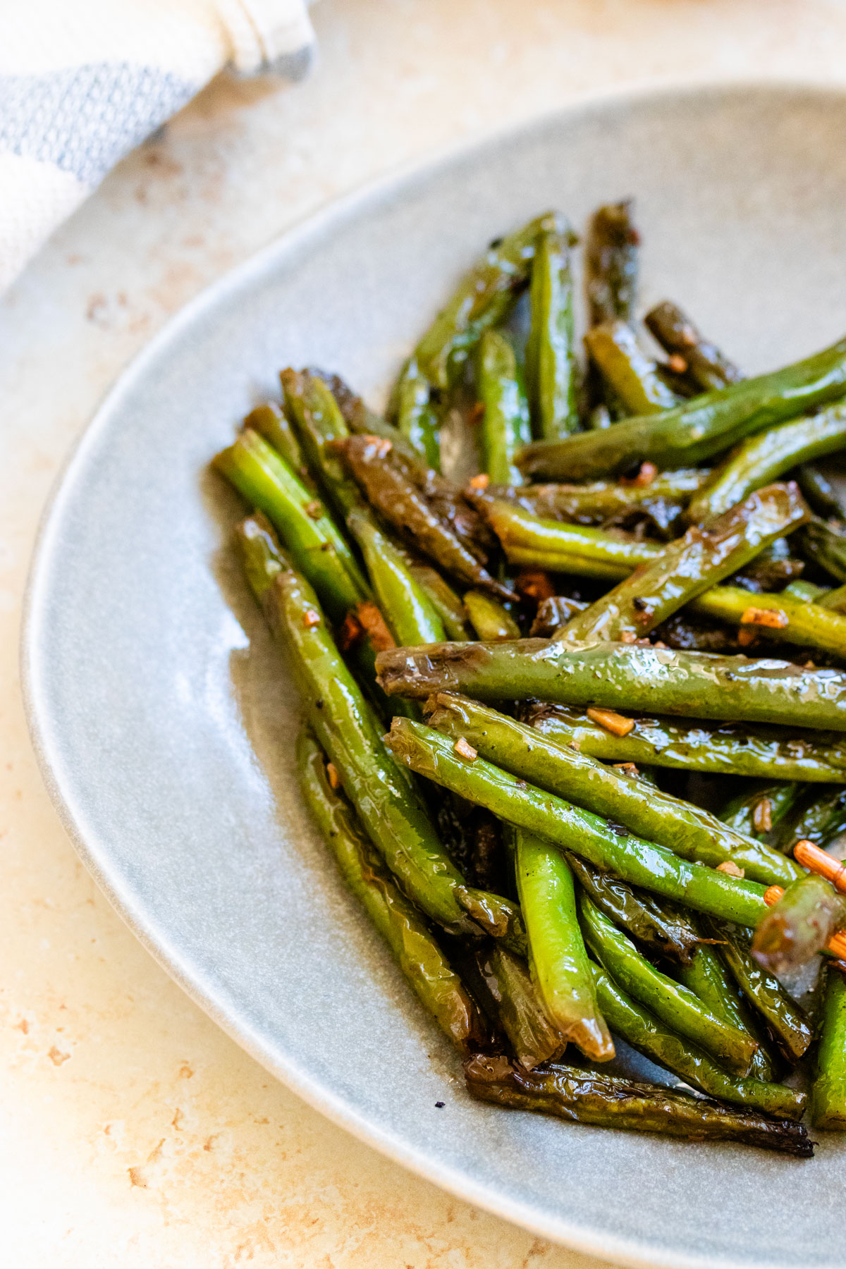 Chinese garlic stir-fry green beans on blue plate.