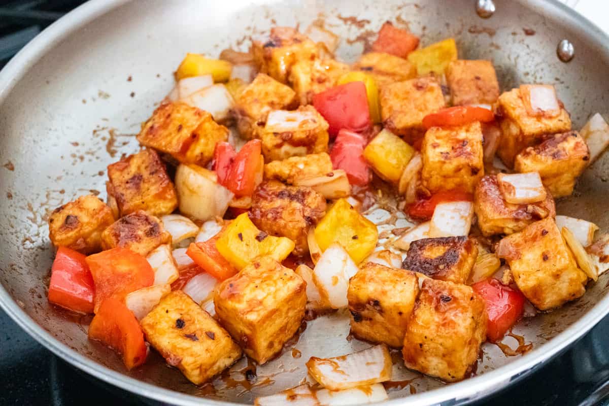 Tofu in pan coated in sweet and sour sauce.