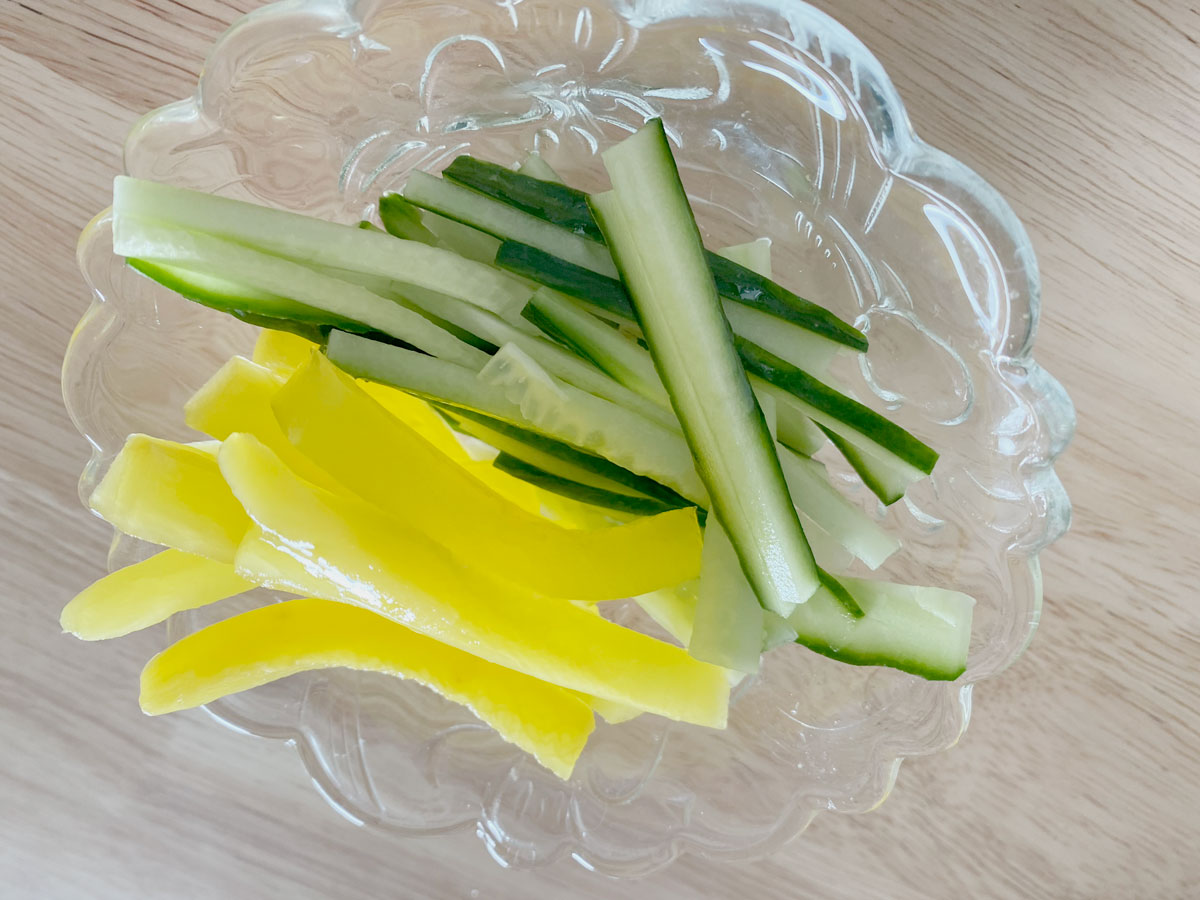 Bowl of julienned cucumbers and sliced pickled daikon.