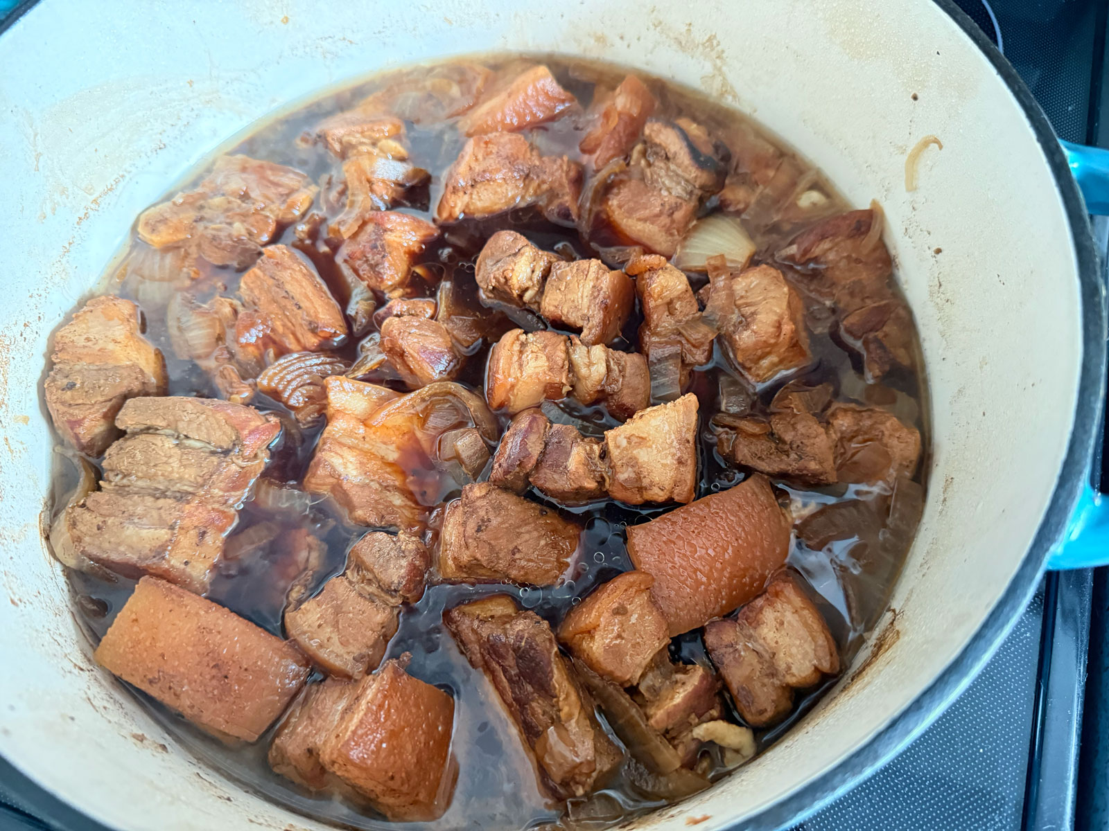 Cook pork belly with aromatics and sauces.